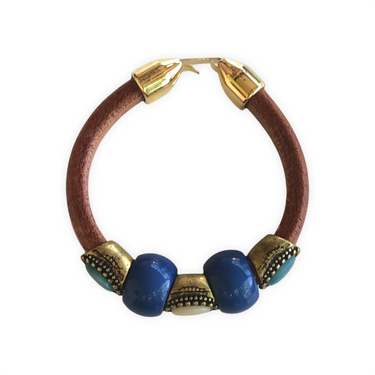 Elegante pulsera de cuero regaliz tostado, con cuentas de Zamak con baño de oro y espectaculares cuentas de cerámica Azules. Combínala con tus prendas de diario.Superior